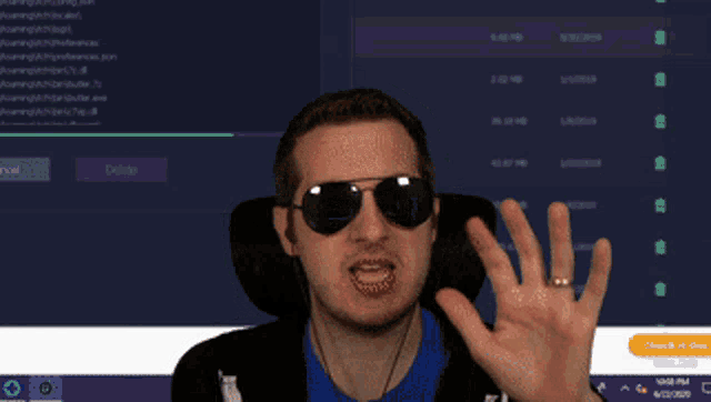 a man wearing sunglasses is making a funny face in front of a computer screen
