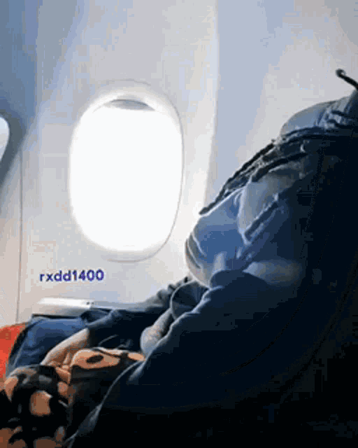 a person sitting on an airplane with a sign that says rxdd1400 on it