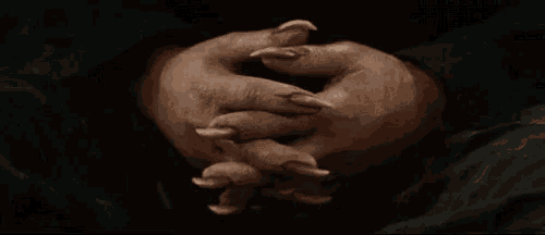 a close up of a person 's hands with long claws on them .