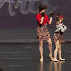 a girl in a red hat is standing on a stage