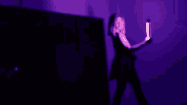 a woman in a black dress holding a microphone in a purple room