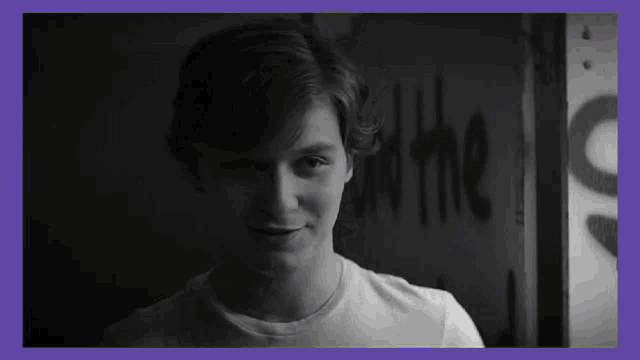 a black and white photo of a young man standing in front of a sign that says " out the "