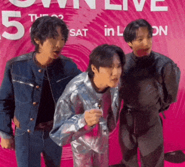 a group of young men are posing for a picture in front of a pink sign that says 5th sat in london .