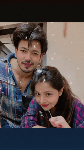 a man and a woman pose for a picture with snow falling on them