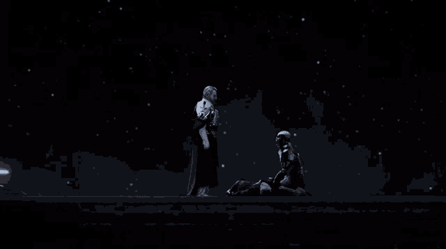 a man standing next to a man laying on the ground in the dark
