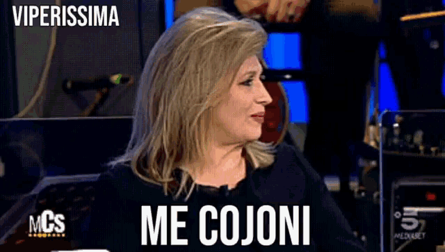a woman says me cojoni while sitting in front of a mcs sign
