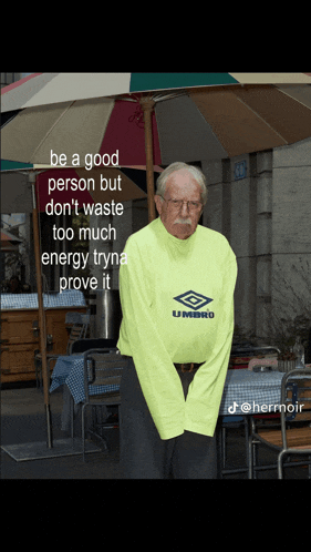a man wearing a neon yellow umbro shirt stands under an umbrella