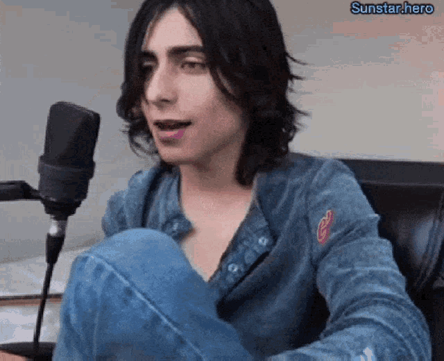 a young man sitting in front of a microphone with the sunstar.hero watermark