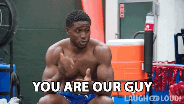 a shirtless man sits in front of an orange cooler and says you are our guy