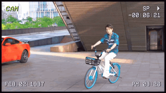 a man is riding a bike in front of a red car and the date february 2 1987