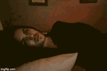 a man with long hair and a beard is laying on a bed with a pillow .