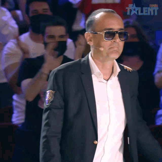 a man in a suit and sunglasses stands in front of a sign that says ' spain talent '
