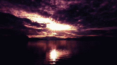 a sunset over a lake with purple clouds