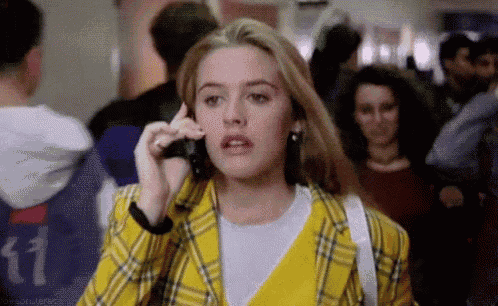 a woman in a plaid jacket is talking on a cell phone in a crowded room .