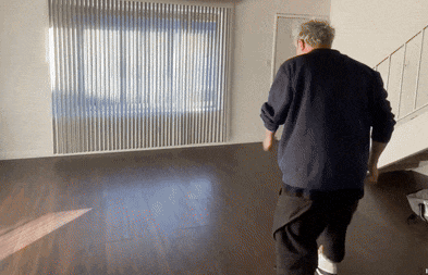a man in a blue sweater is walking in a living room