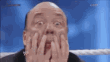 a man is making a surprised face while holding his hands to his face .