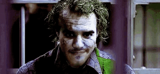 the joker is wearing a purple shirt and a green jacket and has a scar on his face .