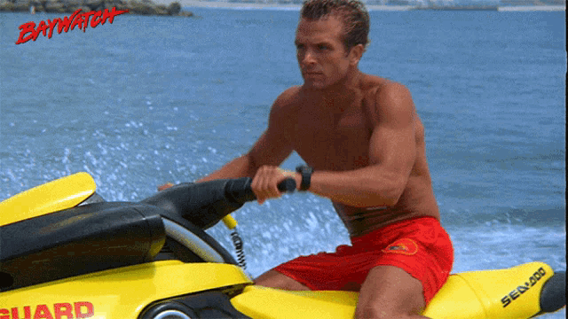 a man in red shorts is riding a yellow jet ski