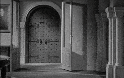 a black and white photo of a door with a picture of a man on the wall behind it