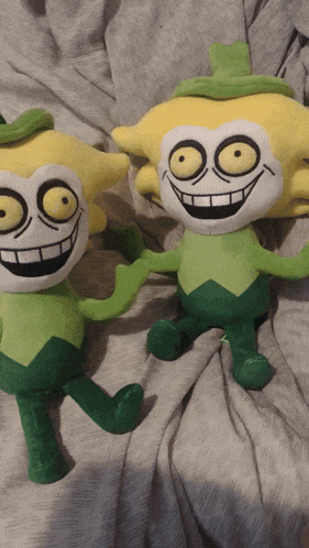 two stuffed cartoon characters are sitting next to each other on a blanket