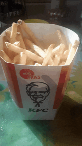 a container of kfc french fries sits on a green table