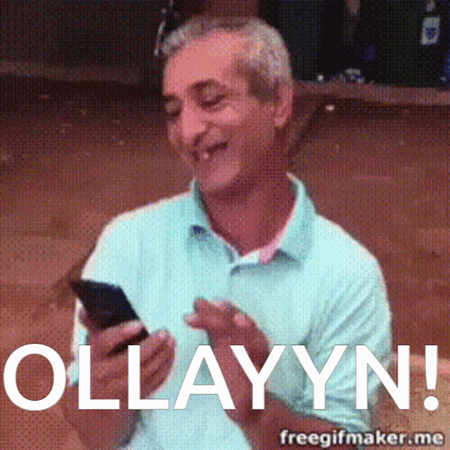 a man in a blue shirt is holding a cell phone and the text ollyyn is above him