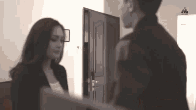 a man and a woman are standing next to each other in front of a door in a black and white photo .
