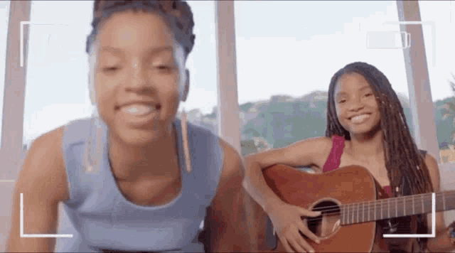two young girls are playing guitars and smiling for the camera .