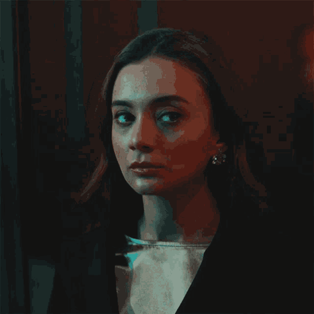 a close up of a woman 's face in a dark room with a red light behind her
