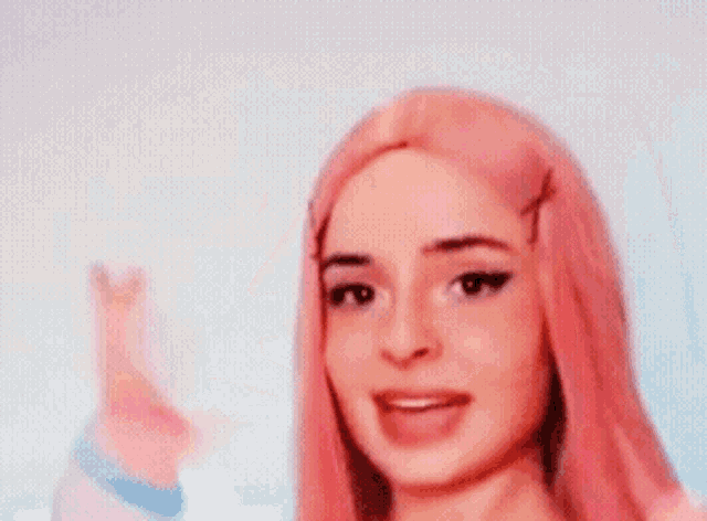 a woman with pink hair is making a funny face while wearing a pink wig and striped gloves .