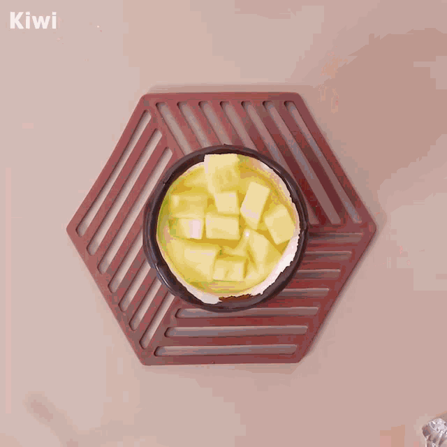 a cherry sits on a table next to a bowl of kiwi