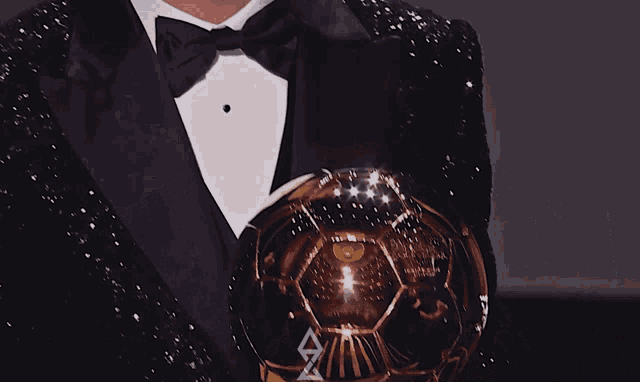 a man in a tuxedo is holding a trophy