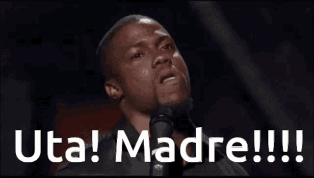 a man stands in front of a microphone with the words " uta madre !!! " behind him