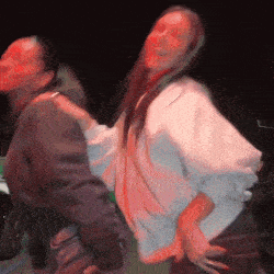 two women are dancing together in a dark room with red lights .