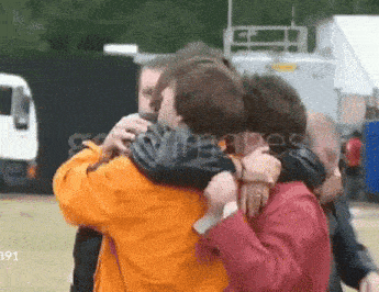 a group of people hugging each other in front of a white truck with the number 491 on it