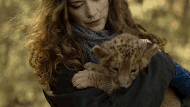 a woman is holding a small cub in her arms