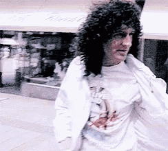 a man with curly hair wearing a white jacket and a white shirt