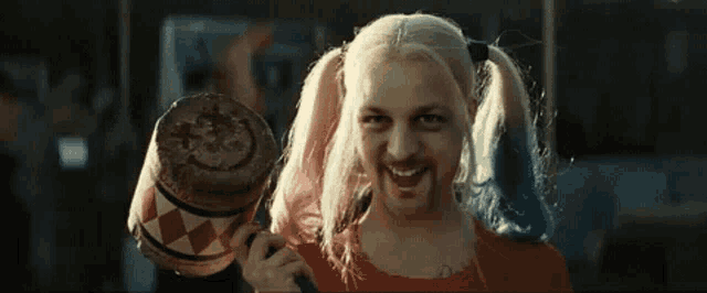 a man dressed as harley quinn from suicide squad is holding a hammer .