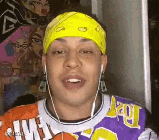 a man wearing a yellow bandana and earphones is talking .