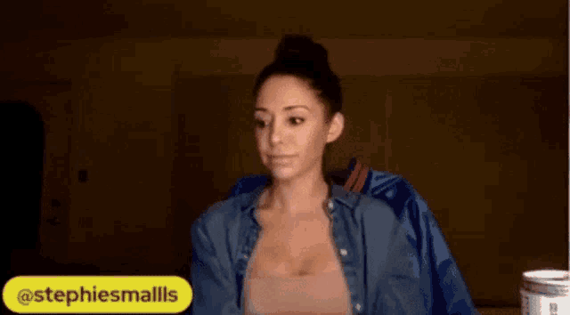 a woman in a blue jacket is making a stop gesture .