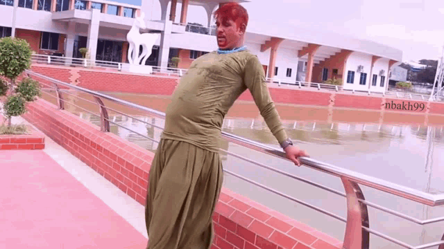 a man with red hair leans on a railing in front of a building that says " nbakh99 "