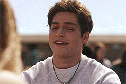 a young man wearing a necklace and a white shirt is smiling