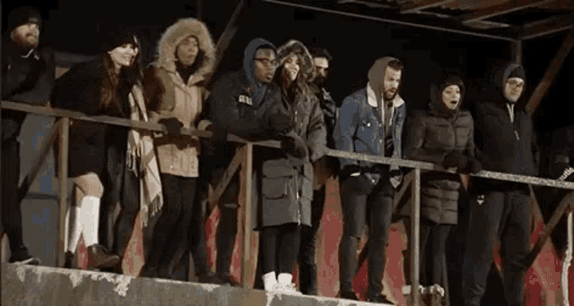 a group of people are standing on top of a railing .
