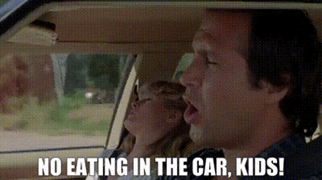 a man is driving a car with a woman sleeping in the back seat and says no eating in the car , kids .