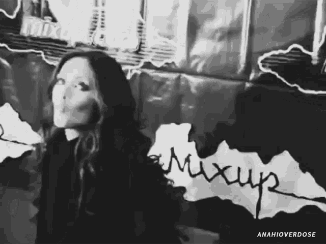 a black and white photo of a woman blowing a kiss in front of a wall that says mixup