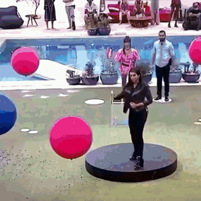 a woman is standing on a platform surrounded by pink balloons