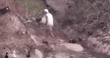 a man in a white hat is standing next to a stream of water