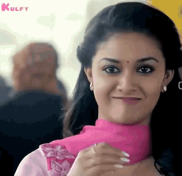 a close up of a woman wearing a pink dress and smiling