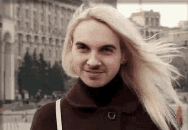 a woman with blonde hair and a man 's face is standing in front of a building .