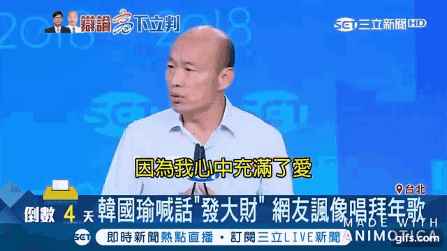 a man in a white shirt is speaking into a microphone in front of a blue background that says sg
